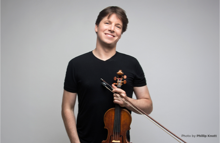Joshua Bell smiling and holding a violin in front of his torso (credit Phillip Knott)